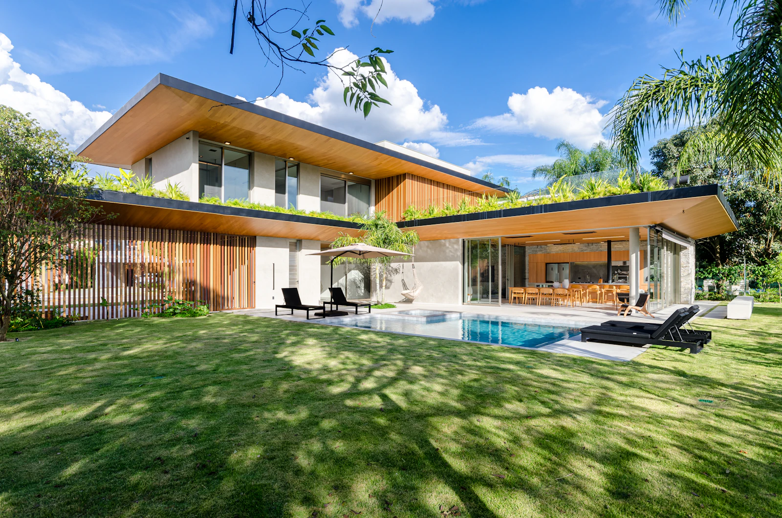 Casa contemporânea concluída, com piscina, jardim gramado e vegetação no entorno.