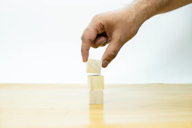 A hand is placing a block of wood on a table