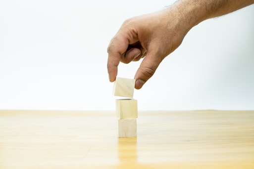 A hand is placing a block of wood on a table