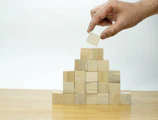 A hand is placing a piece of wood into a pyramid