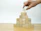 A hand is placing a piece of wood into a pyramid