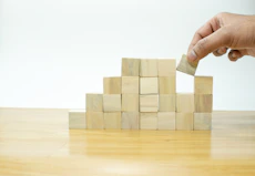 A person placing a block into a pile of wooden blocks