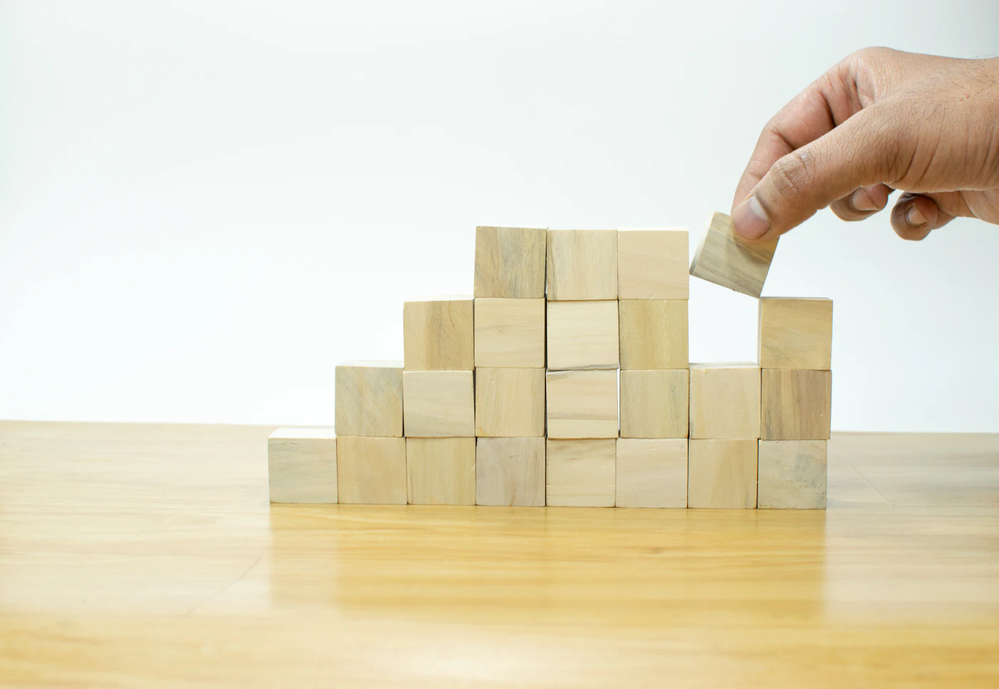 木のブロックを一段ずつ積み上げる手