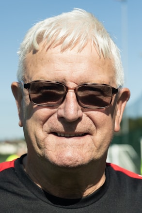A man with white hair wearing sunglasses and a black shirt