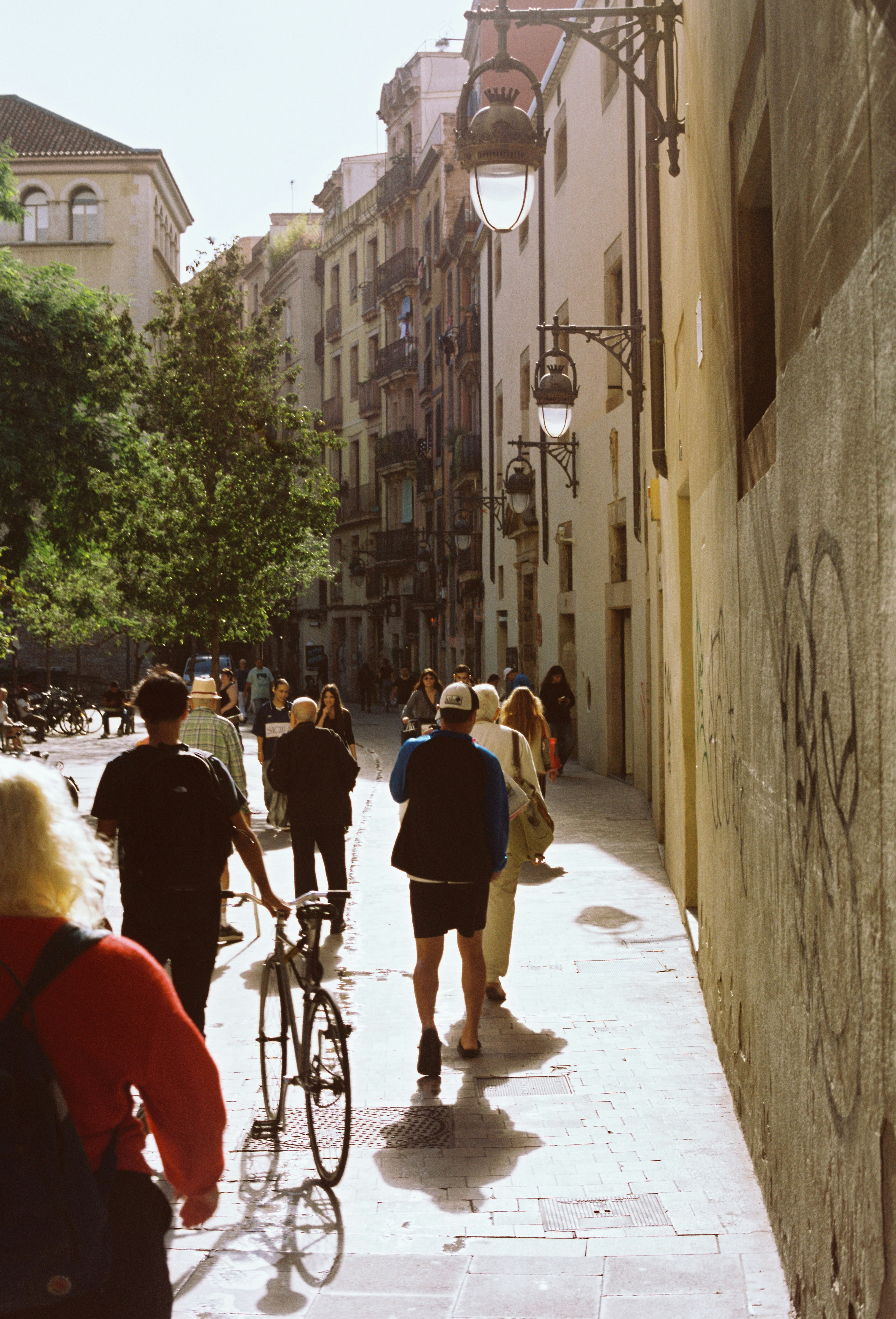 A group of people walking down a street next to tall buildings
