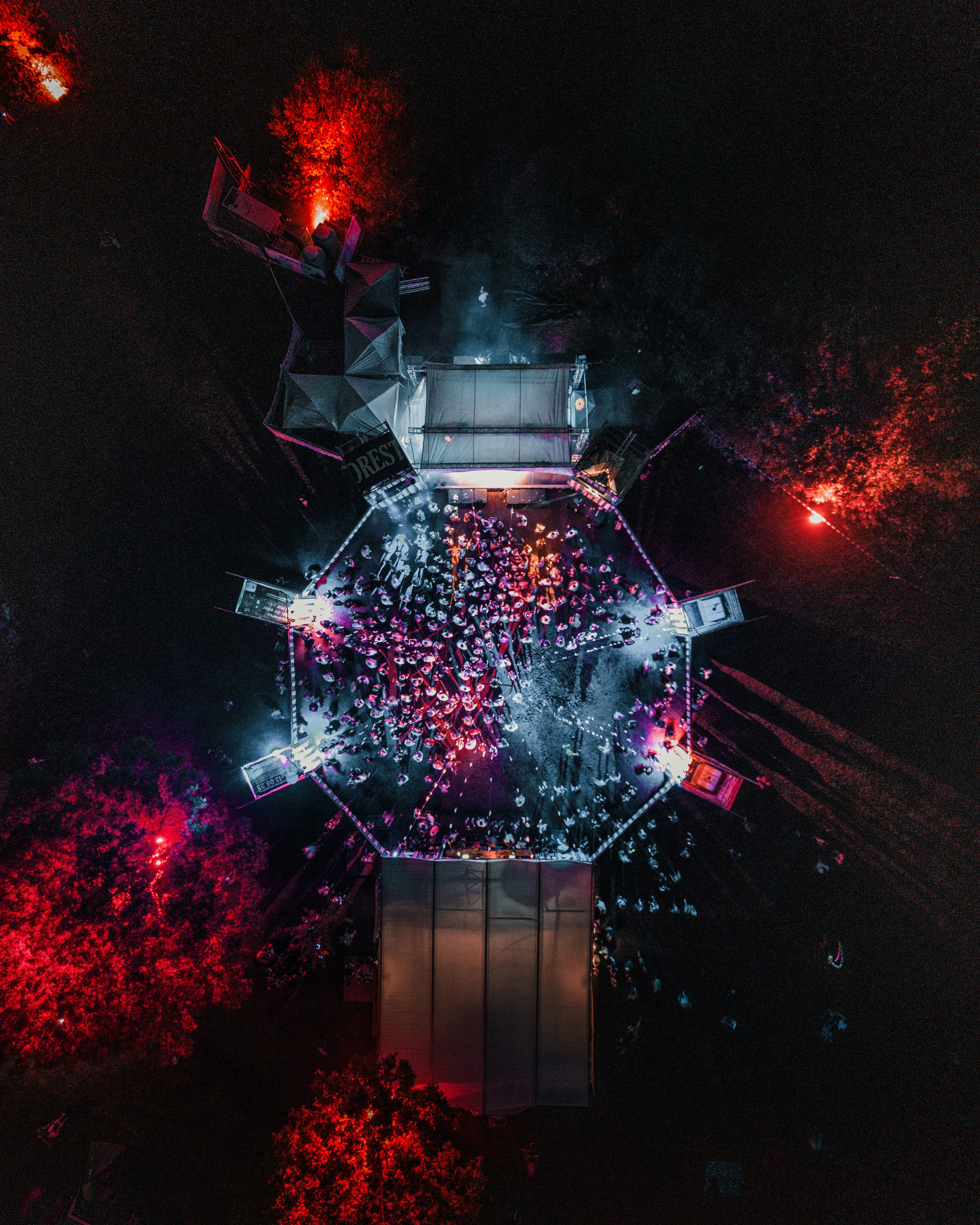 Escenario de festival de música latina con iluminación dramática, artistas en silueta, multitud vibrante, luces de escenario azul profundo y ámbar