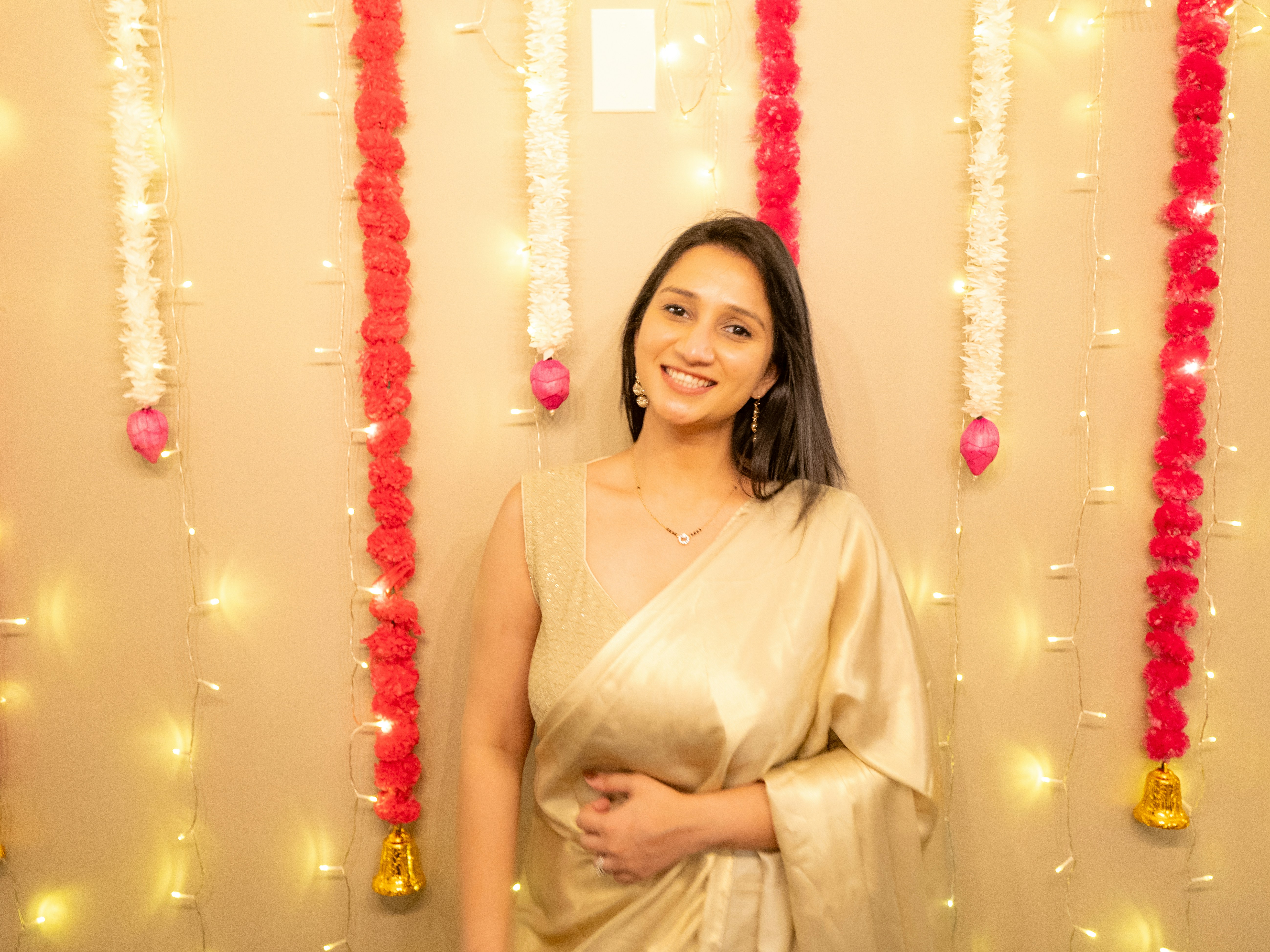 Woman in beautifully draped embroidered saree with gold border, festive ambiance