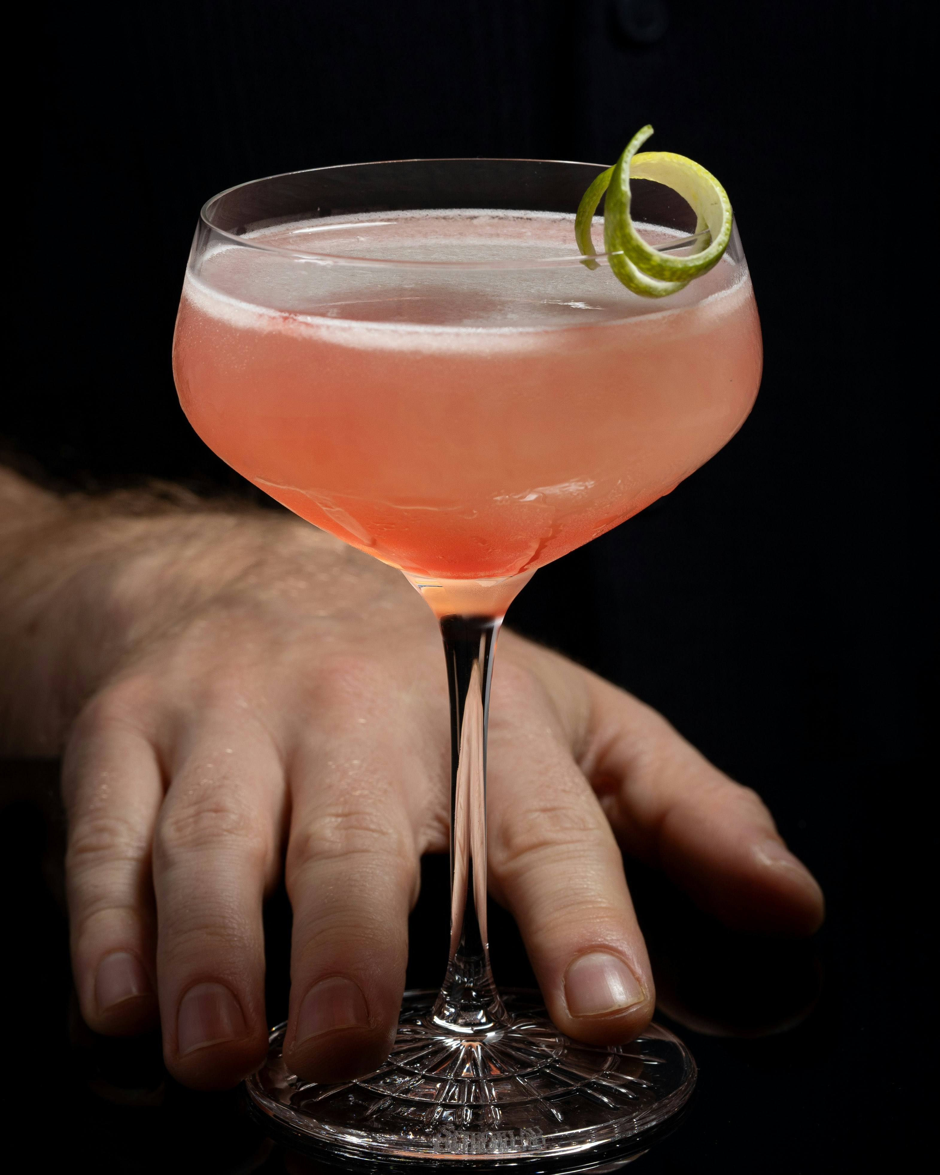 A person holding a cocktail glass with a lime garnish