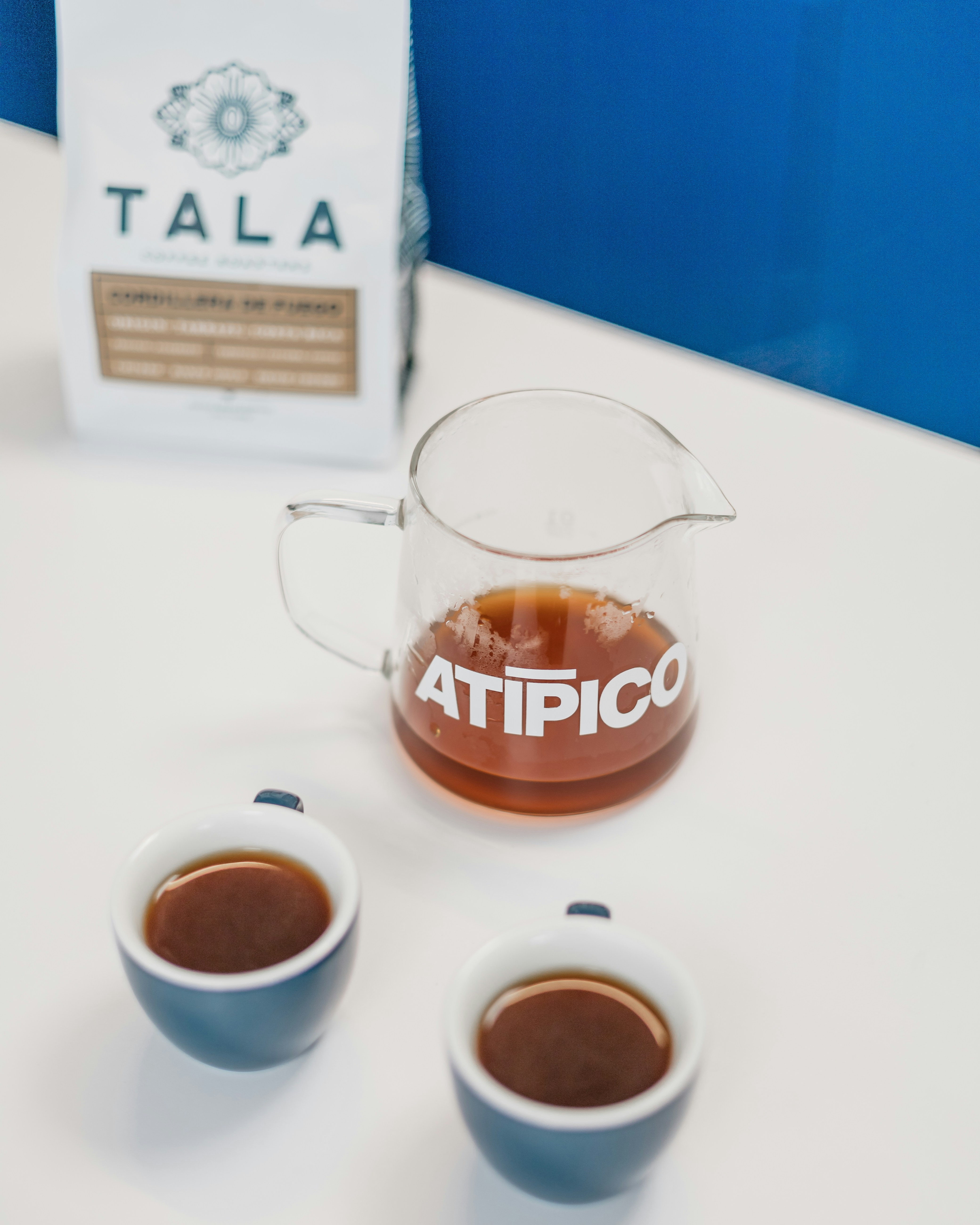 Two cups of tea sit next to a bag of tea