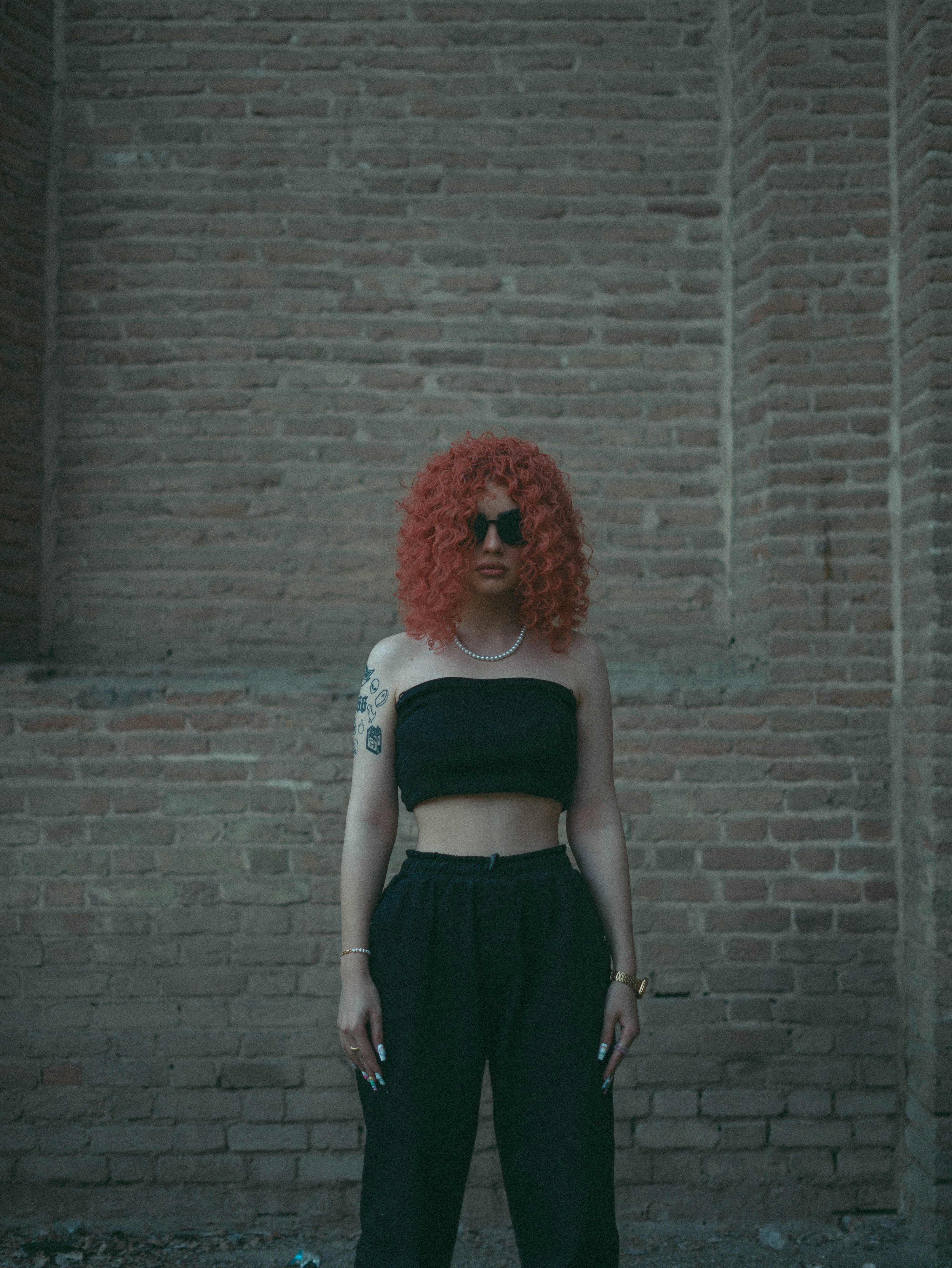 A woman with red hair standing in front of a brick wall photo – Free ...