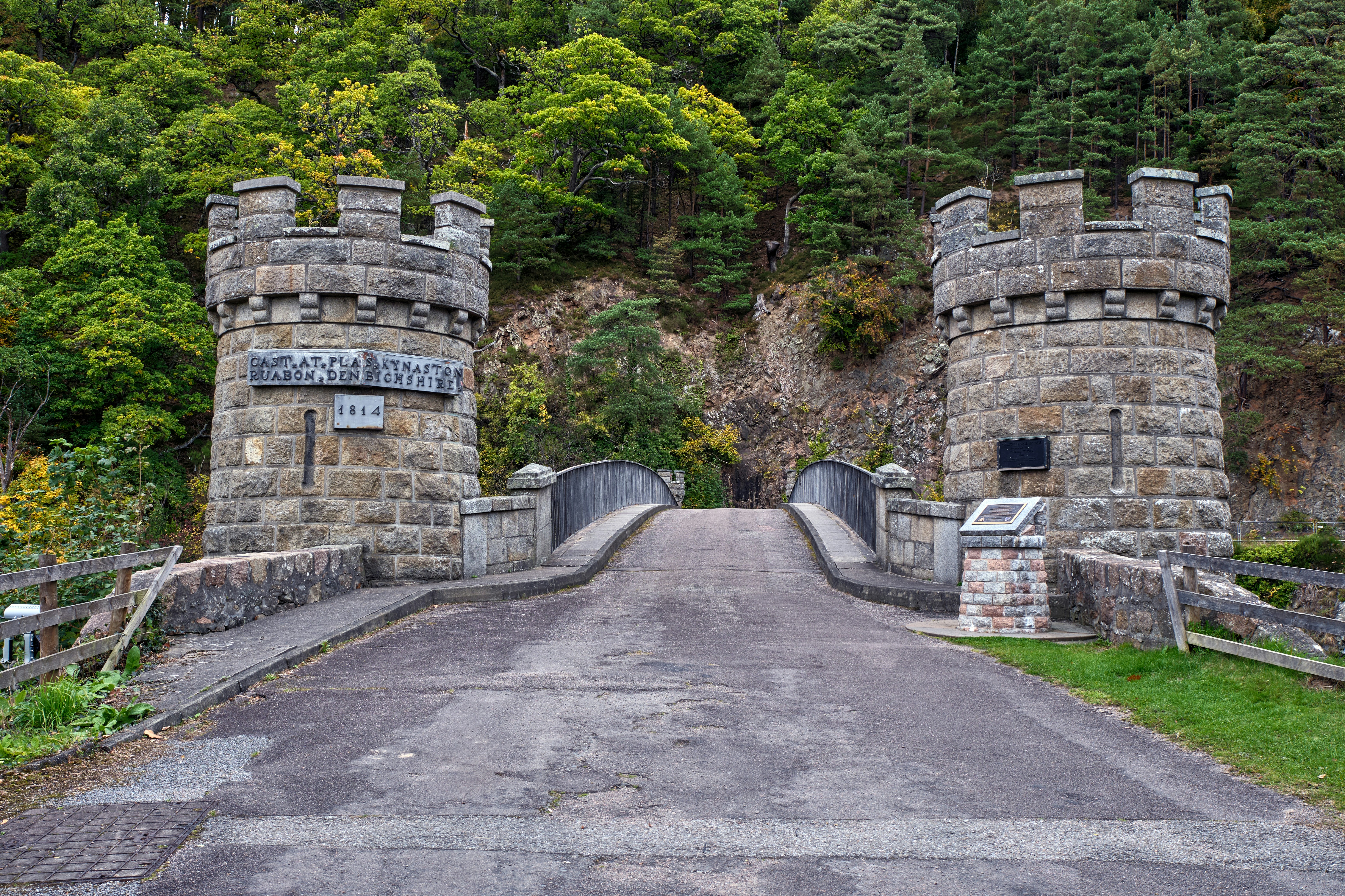 A stone bridge with two gates leading to a forest