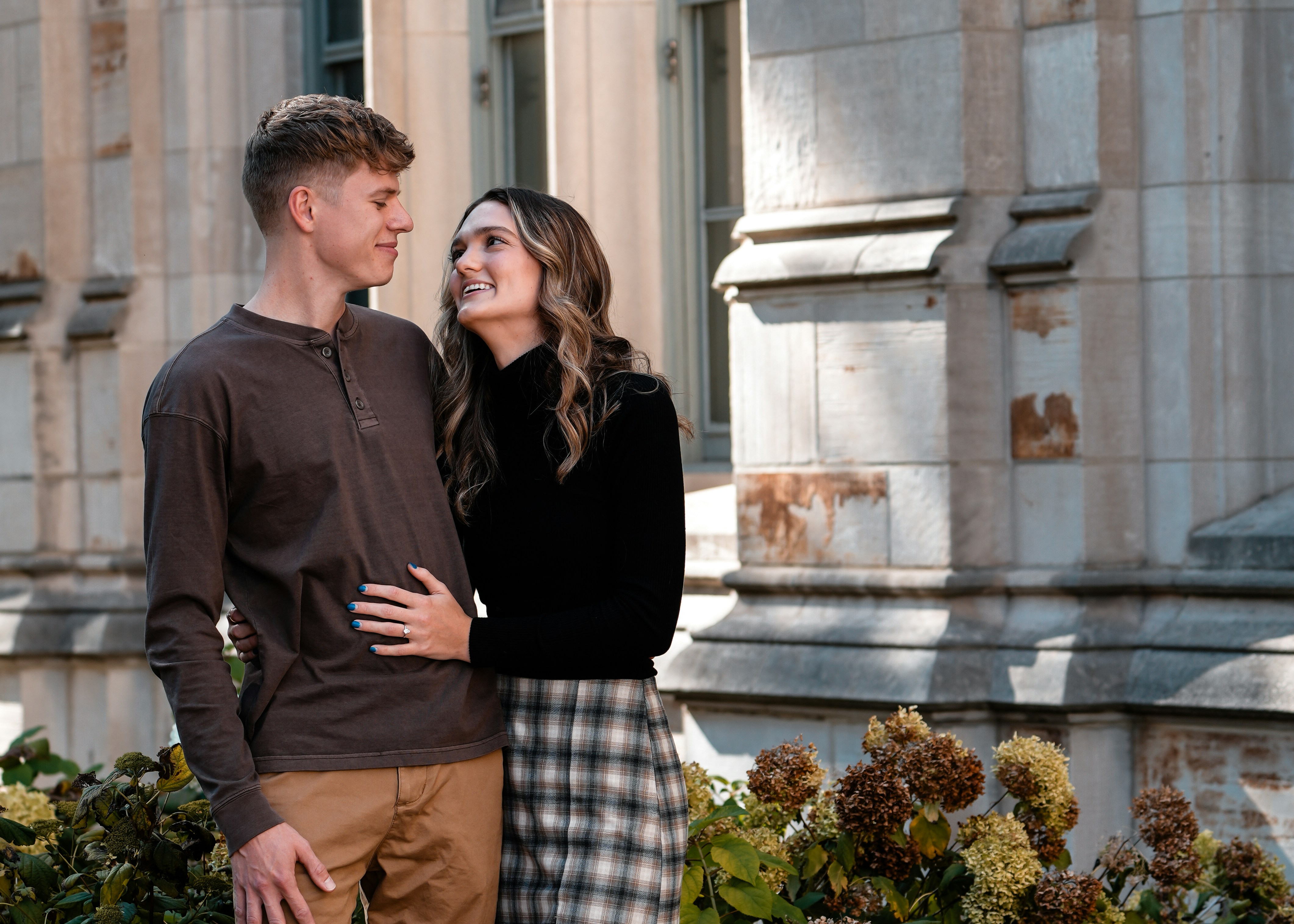 A man and woman standing next to each other in front of a building