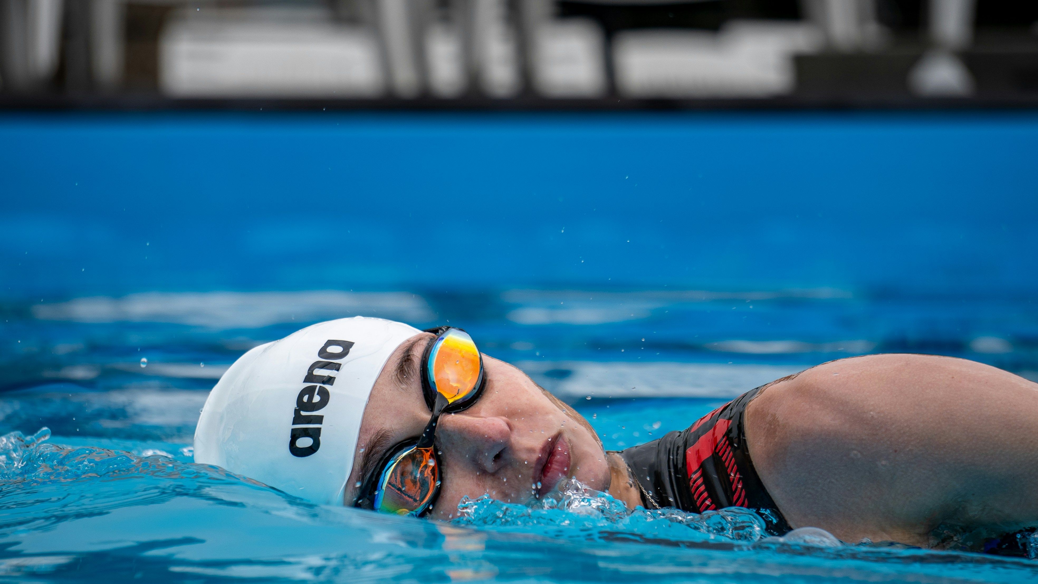 A man swimming in a pool with goggles on