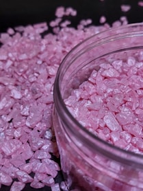 A glass jar filled with pink crushed sugar