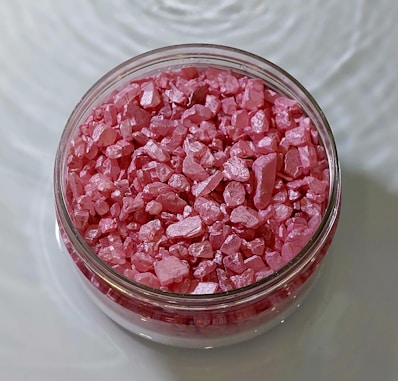 A jar filled with pink colored rocks on top of a table