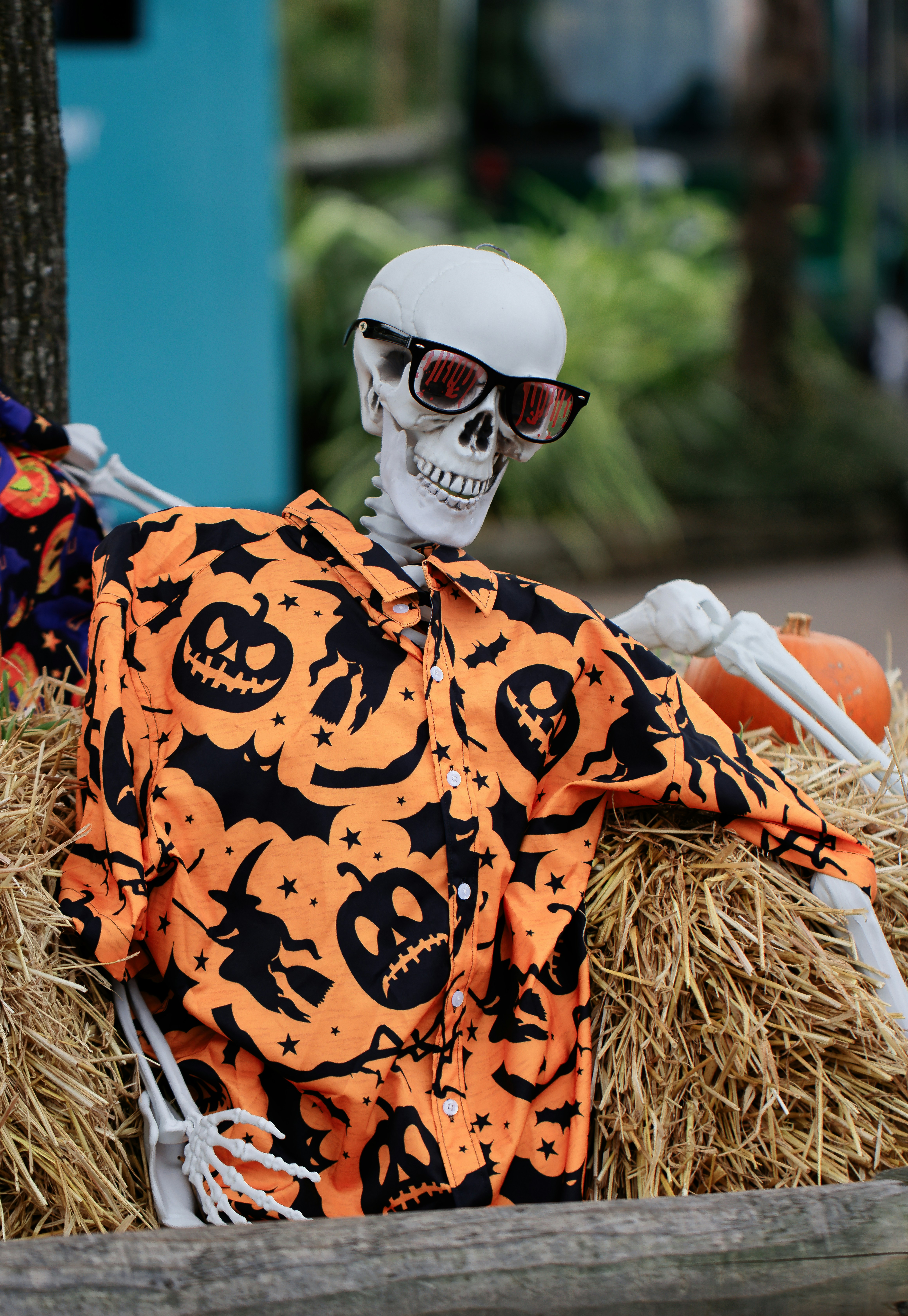A skeleton in a pumpkin costume sitting in a pile of hay
