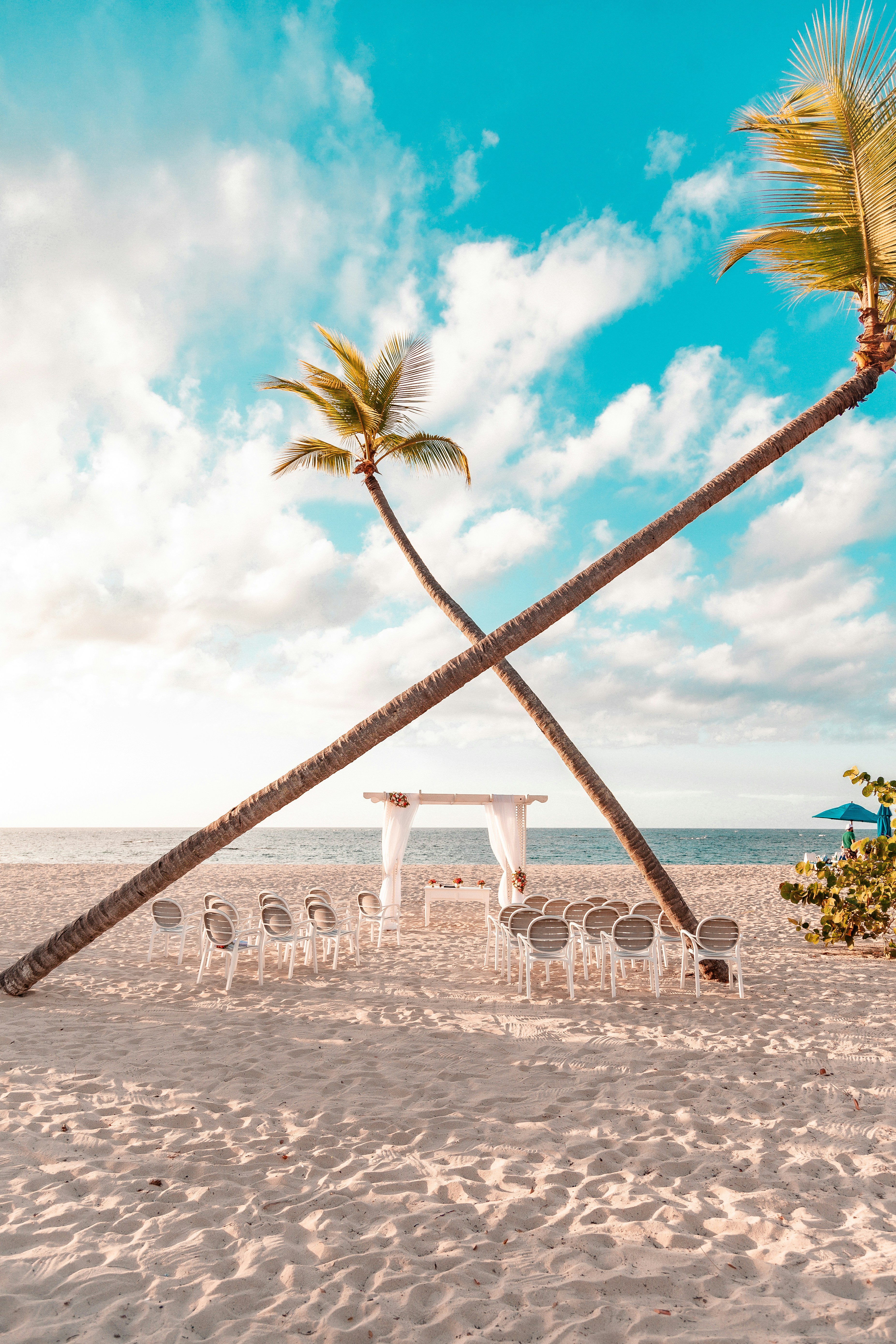 Elegant tropical beach wedding setup with flower arch and candles at sunset