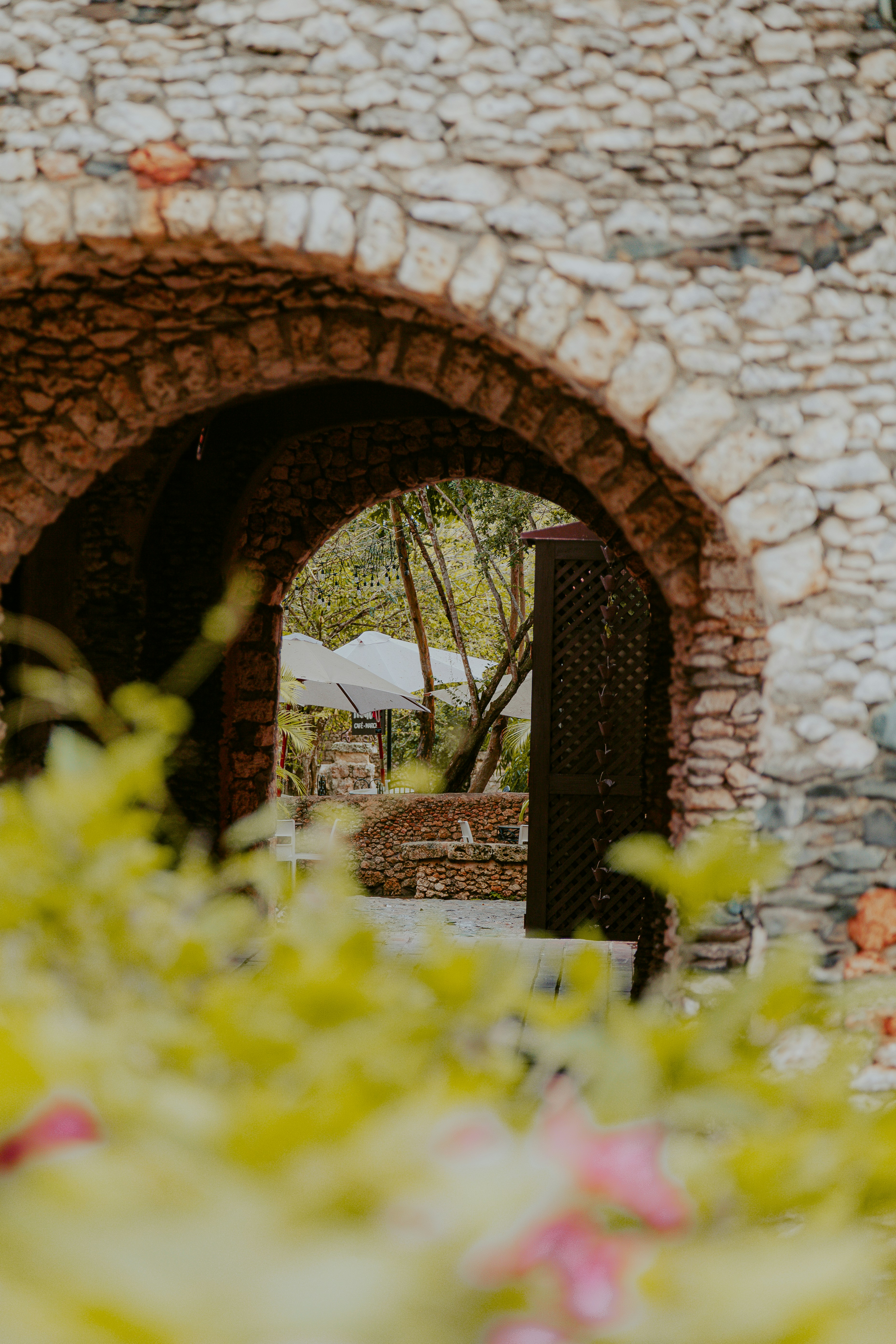 A bride and groom walking through a stone archway
