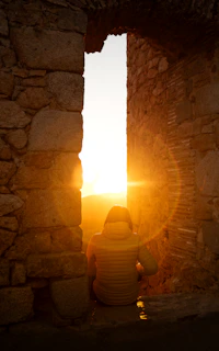 A person sitting in front of a window at sunset