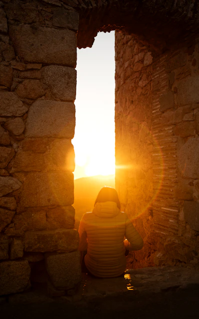 A person sitting in front of a window at sunset
