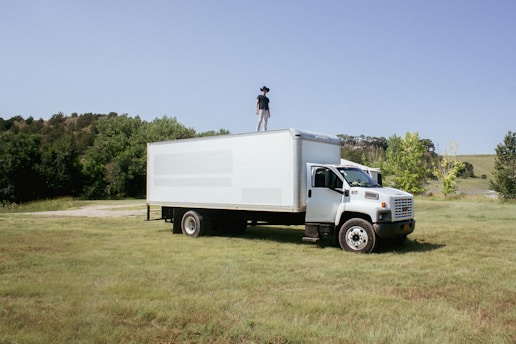 A man standing on top of a truck in a field