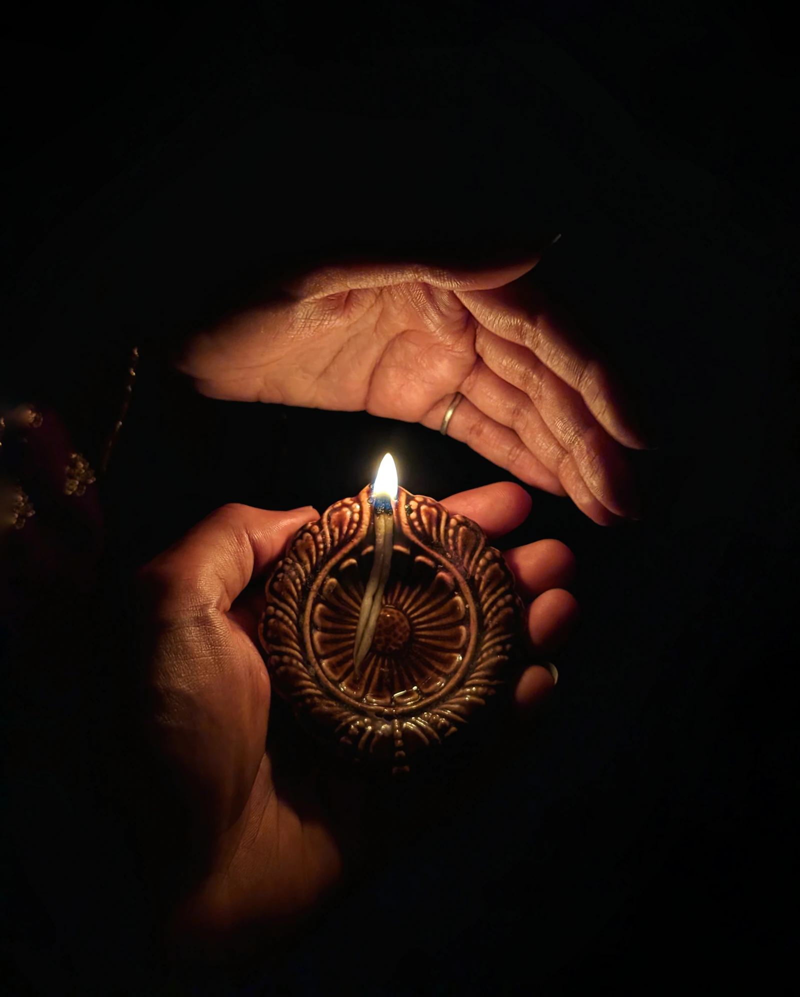 A lit lamp held in cupped hands.