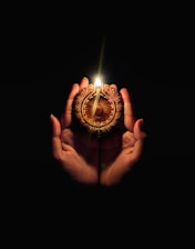 A person holding a lit candle in their hands