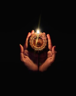 A person holding a lit candle in their hands