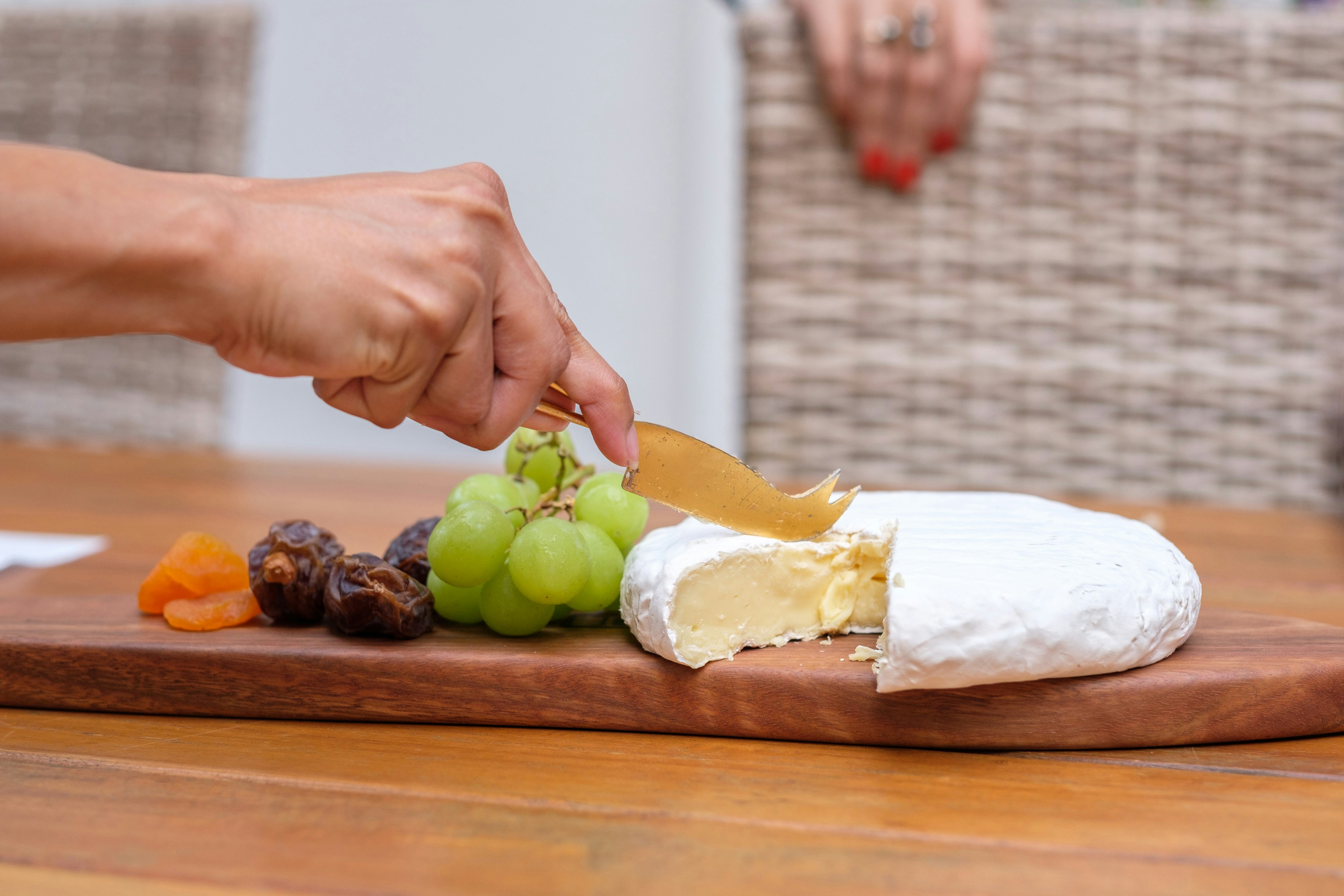 A person cutting a piece of cheese on a cutting board