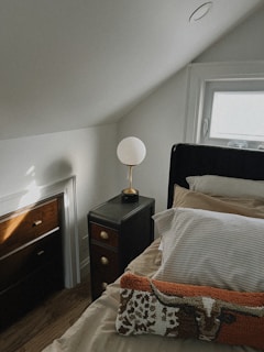 A bedroom with a bed, nightstand, and window