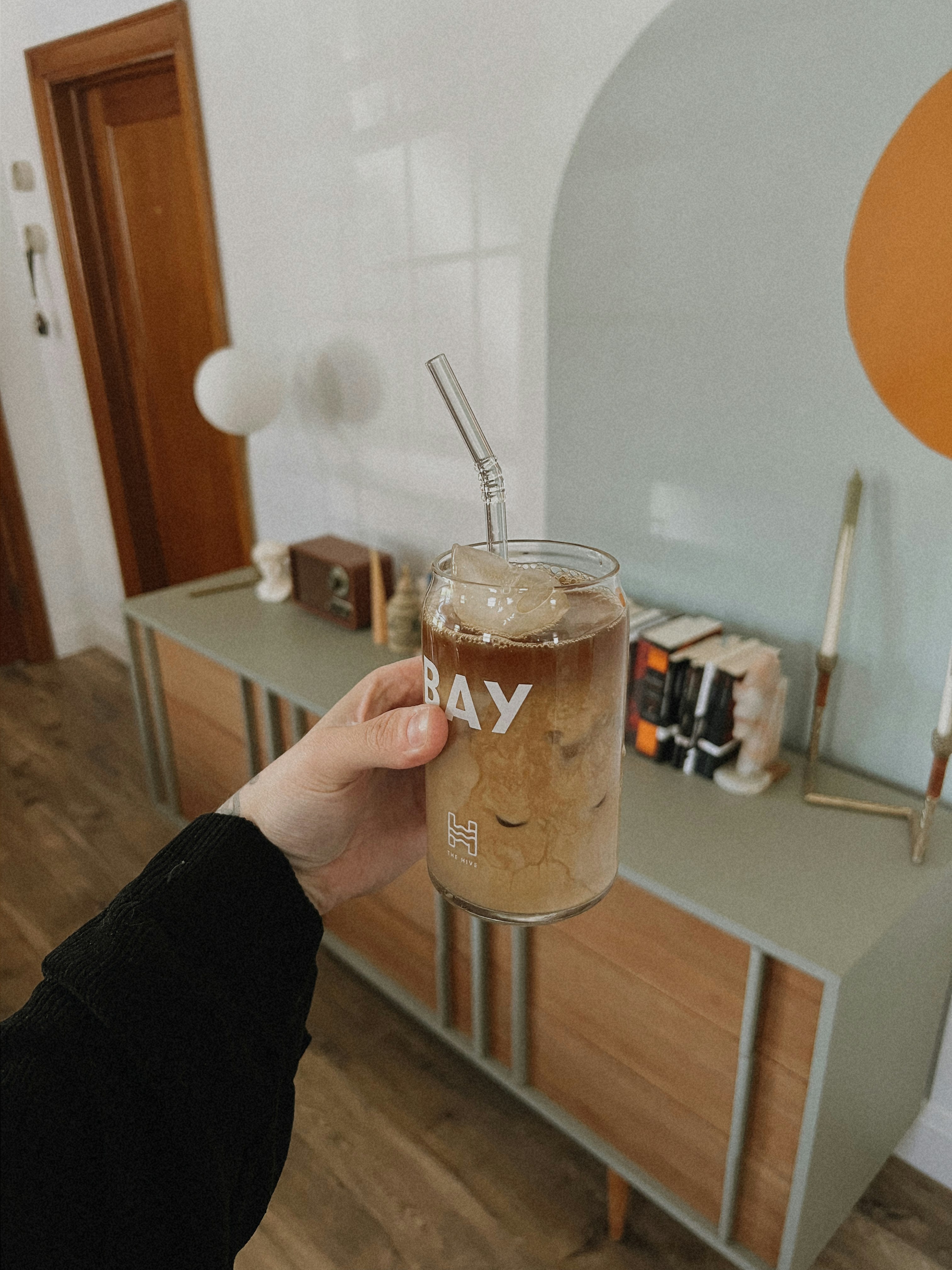 A person holding a mason jar with a straw in it