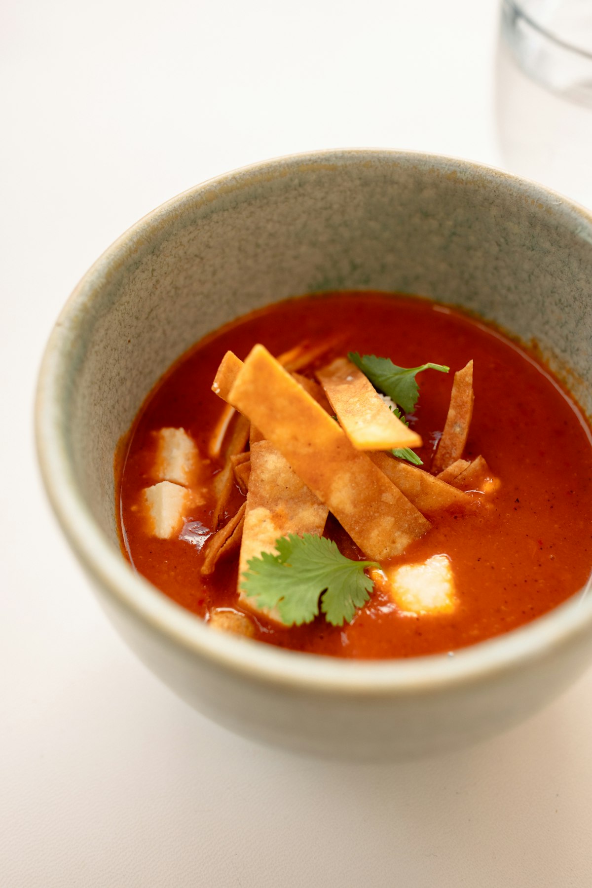 Mexican tortilla soup with shredded chicken, black beans, avocado slices and lime wedge on the side