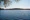 A body of water surrounded by trees and a hill