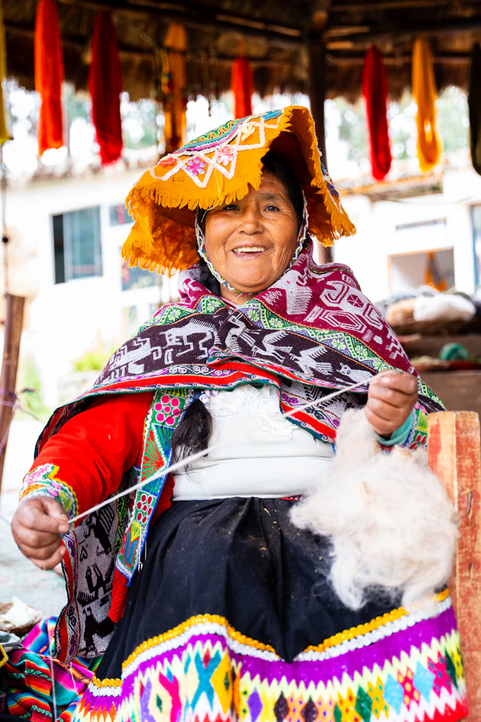 Senhora andina sorridente fiando lã de alpaca em Cusco
