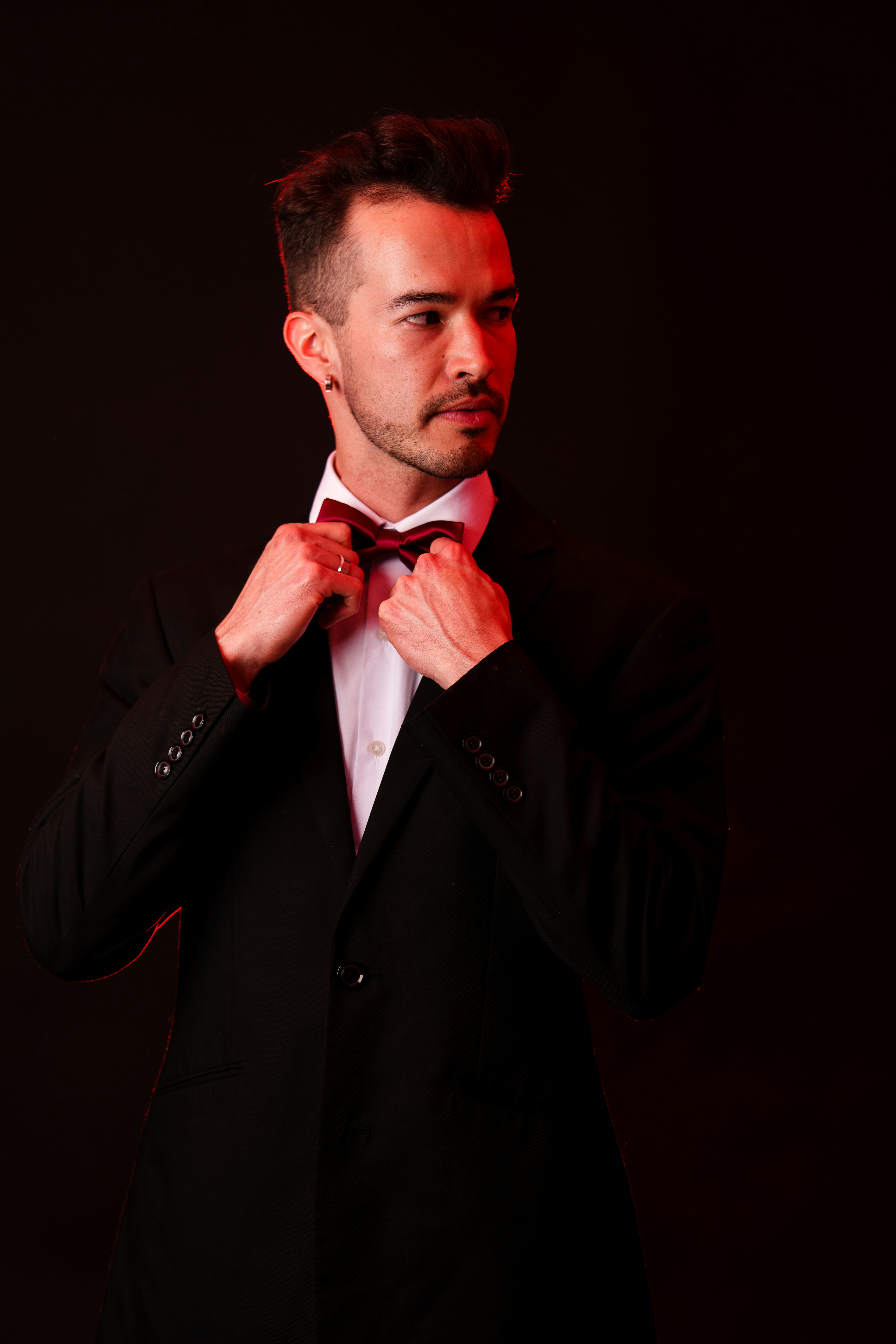 A man in a tuxedo adjusting his bow tie