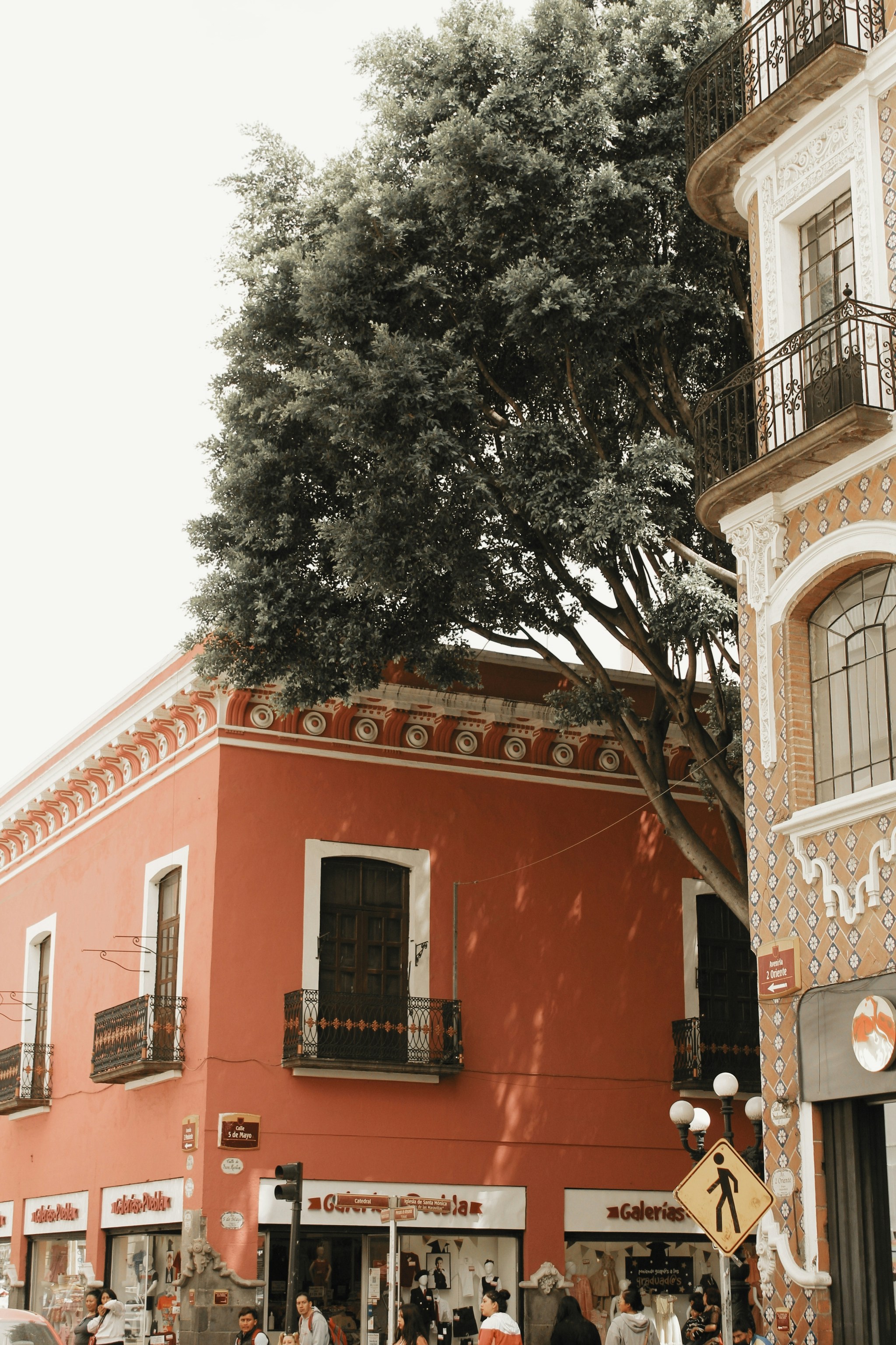 A group of people walking down a street next to a tall building