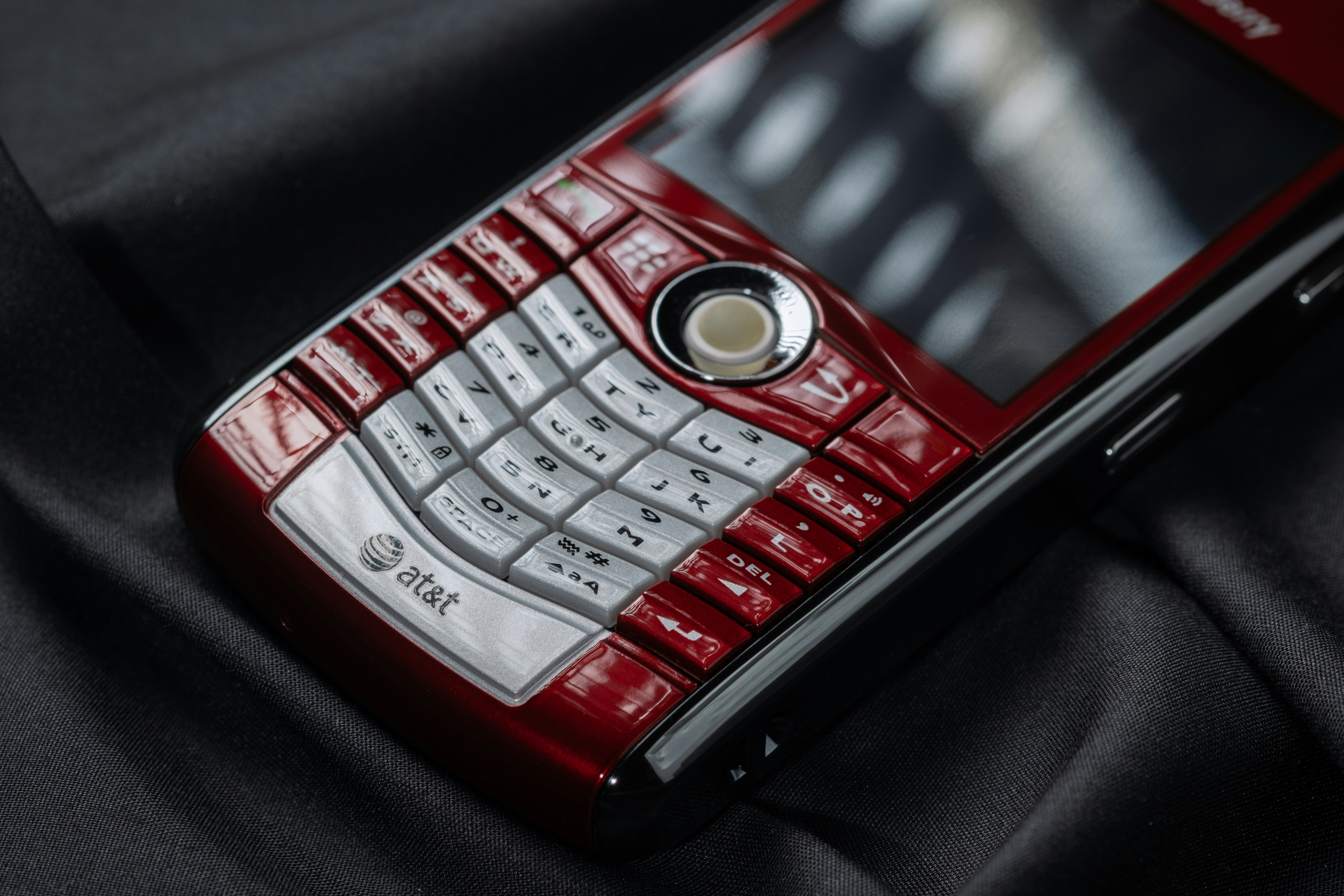 A red cell phone sitting on top of a black cloth
