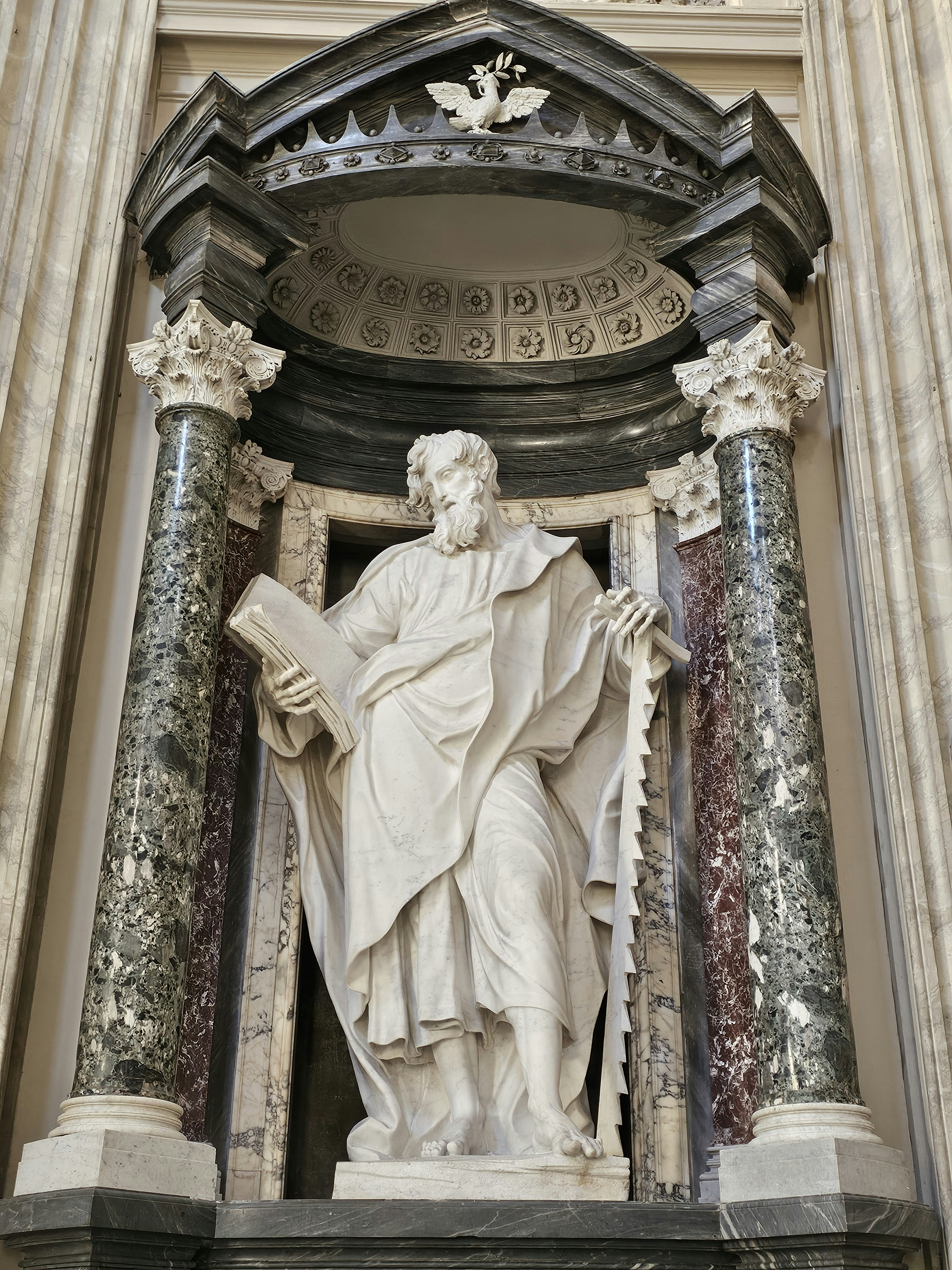 A statue of a man holding a book in front of a building