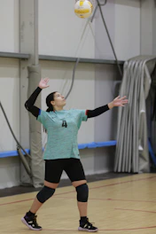 A woman is playing volleyball in a gym