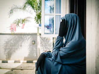 A woman in a blue veil sitting on a bench