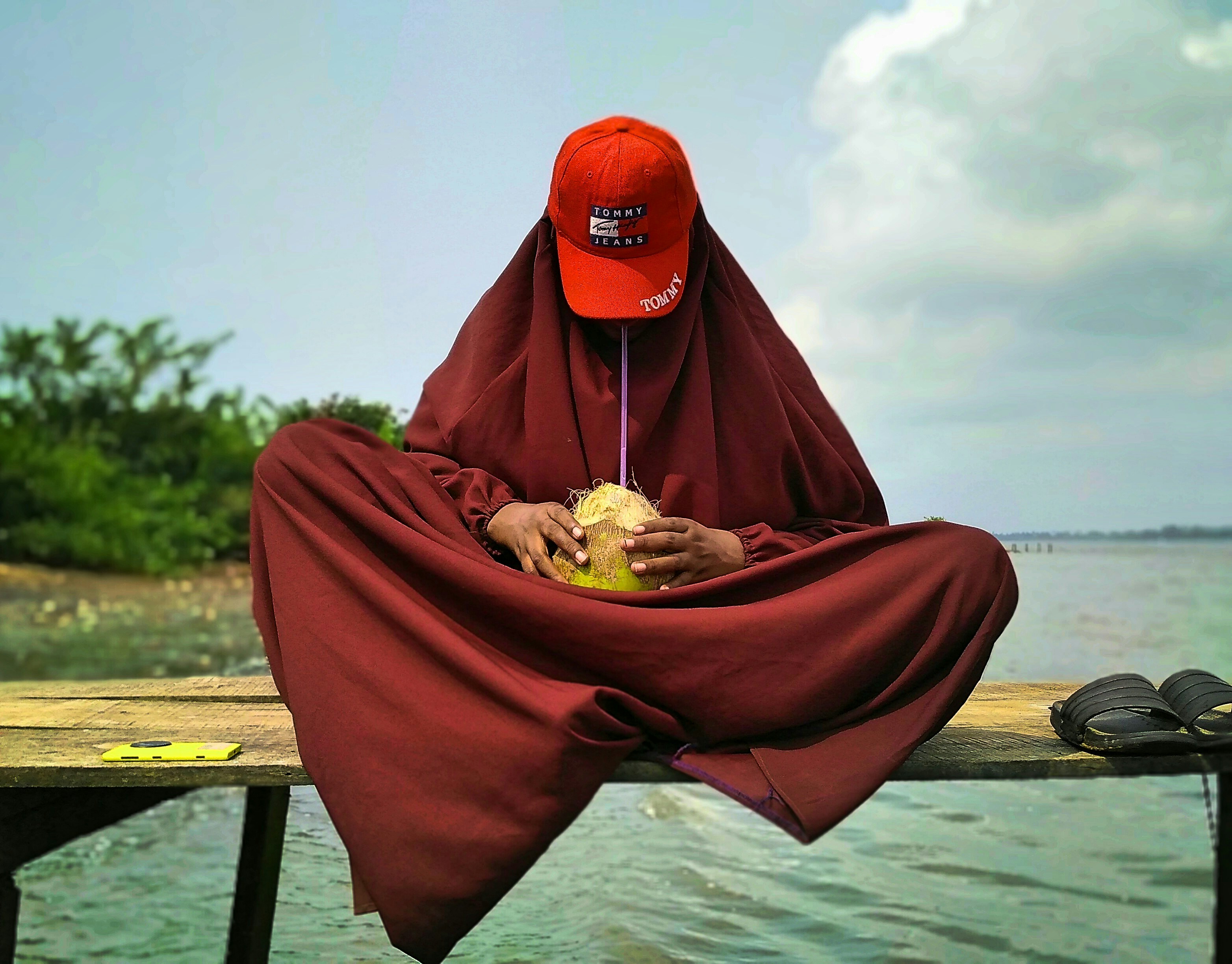 A person sitting on a dock with a hat on