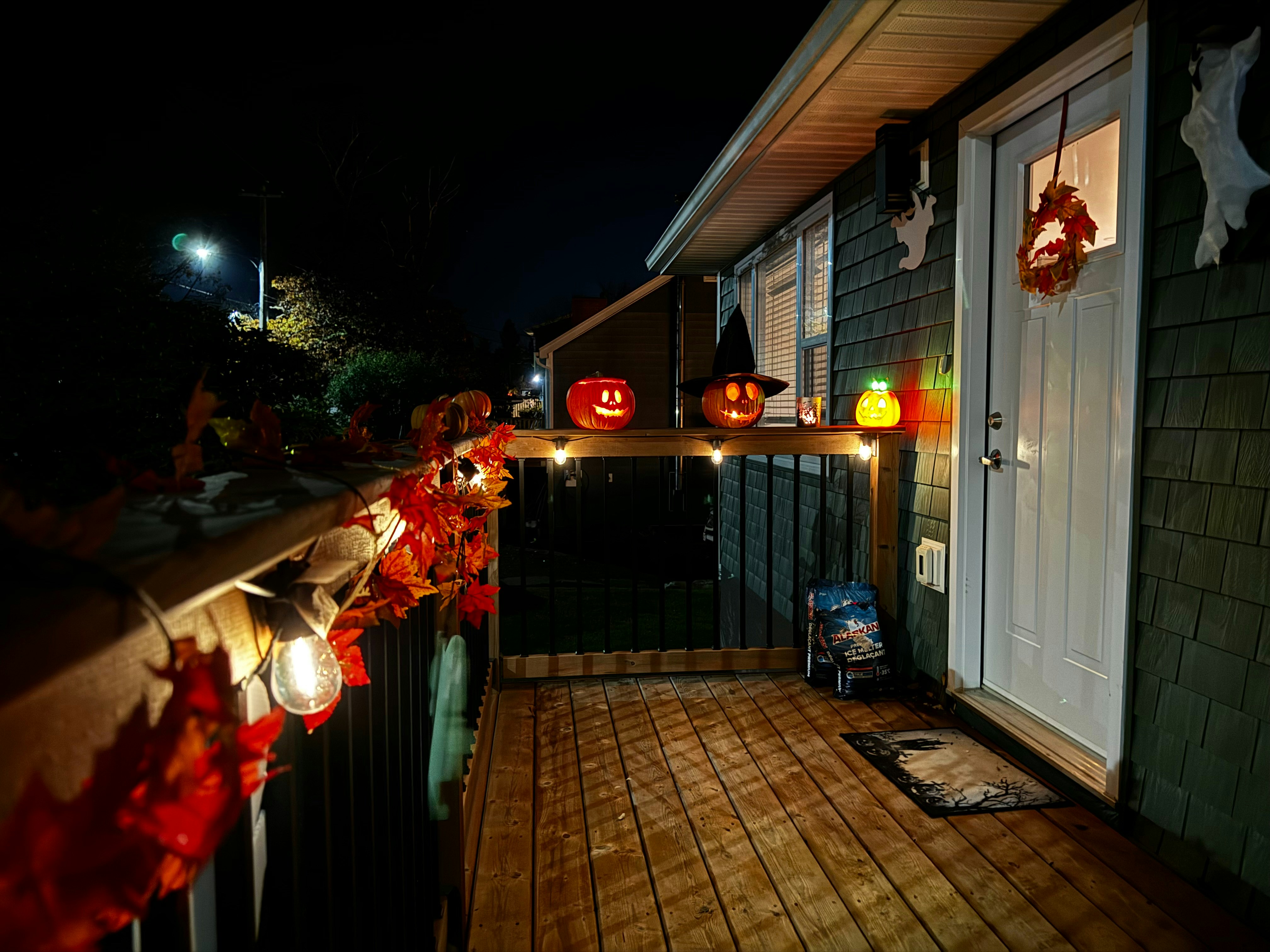 Porch decorated for Halloween with glowing jack-o'-lanterns and lights