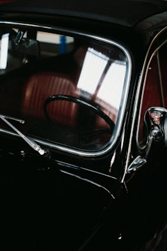 A black car parked in a garage next to another car