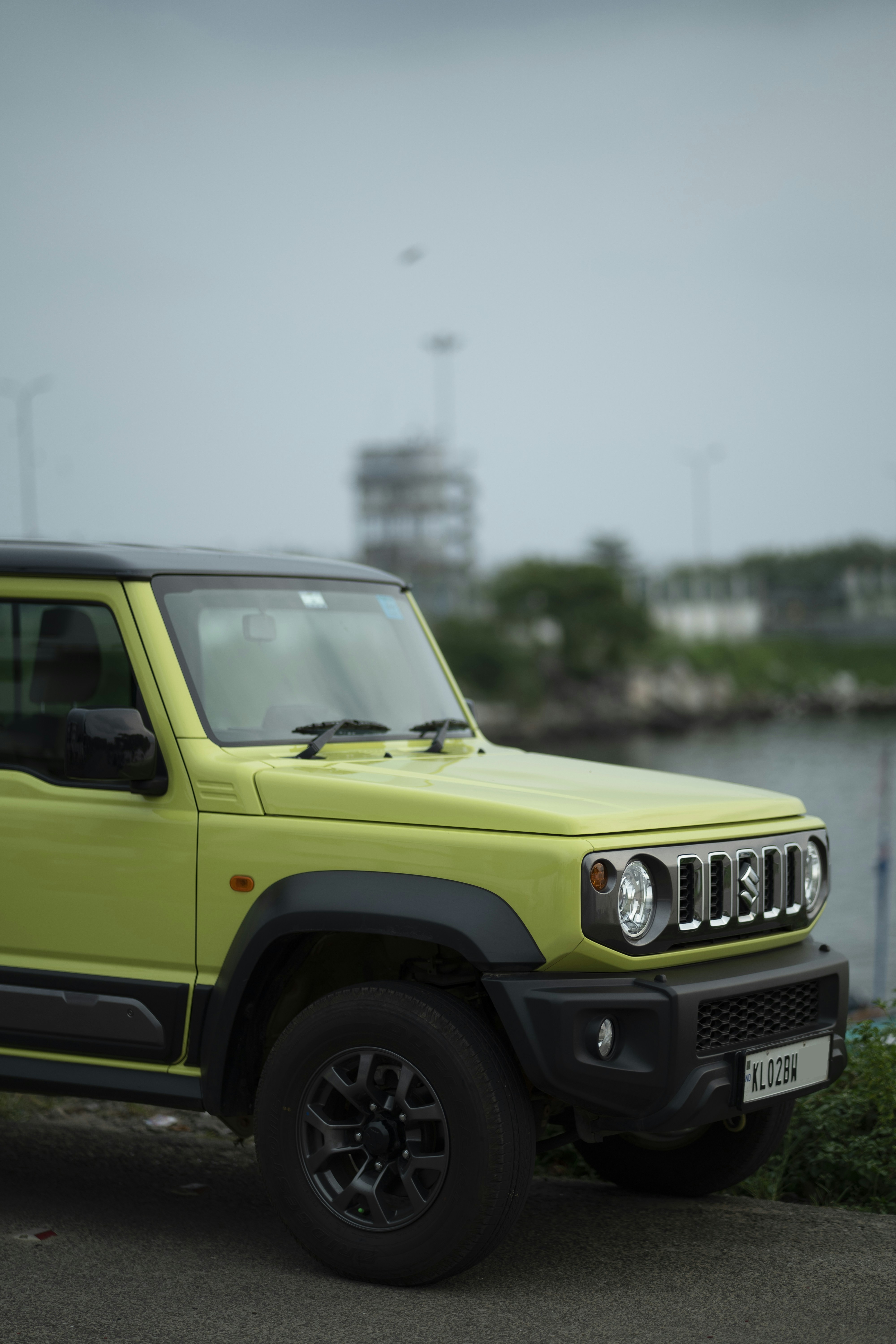 A bright yellow jeep parked next to a body of water
