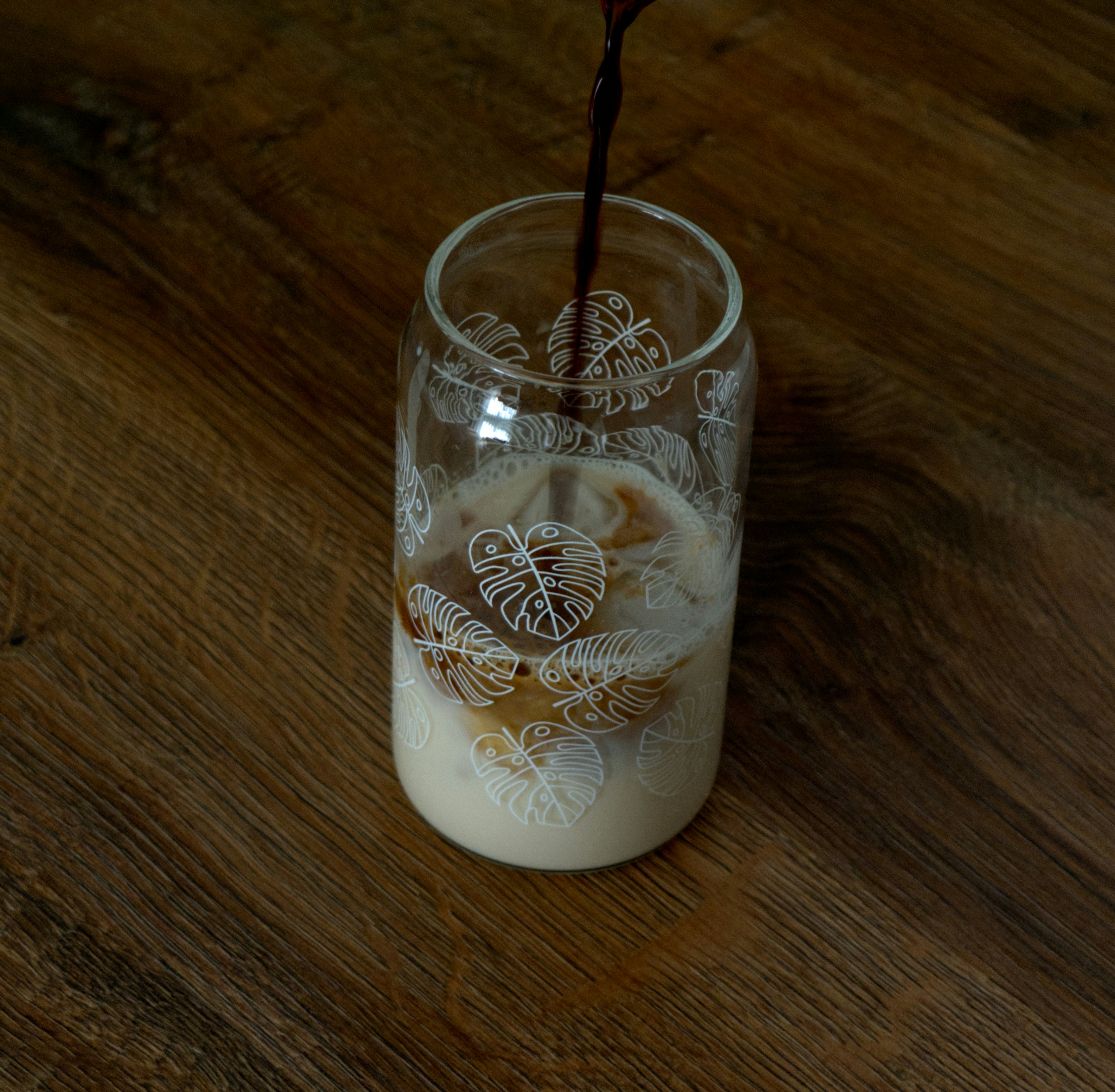 A glass filled with liquid sitting on top of a wooden table