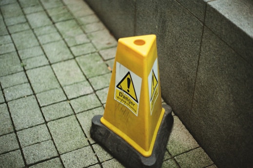 A yellow caution sign sitting on top of a sidewalk