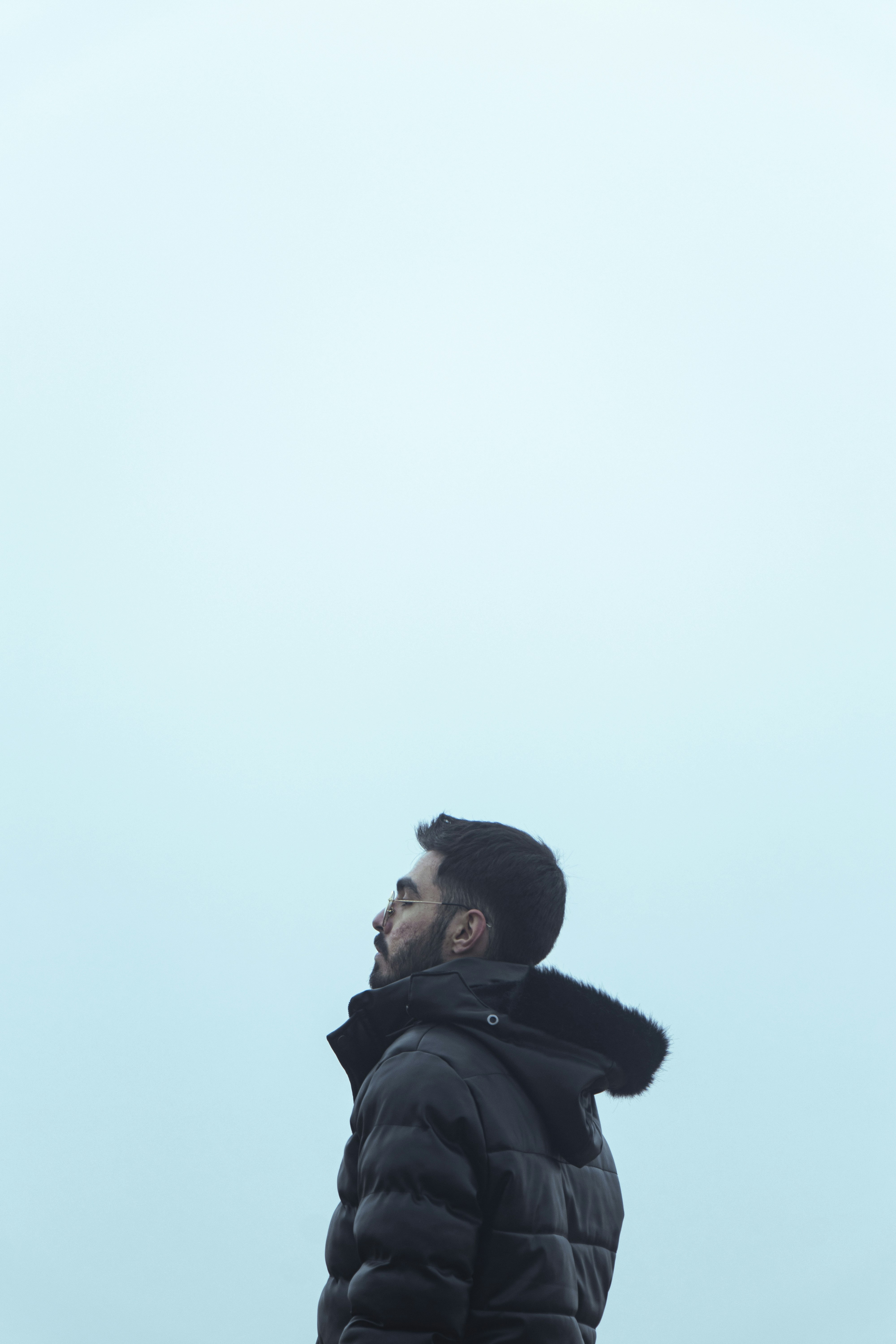 A man standing in front of a kite flying in the sky