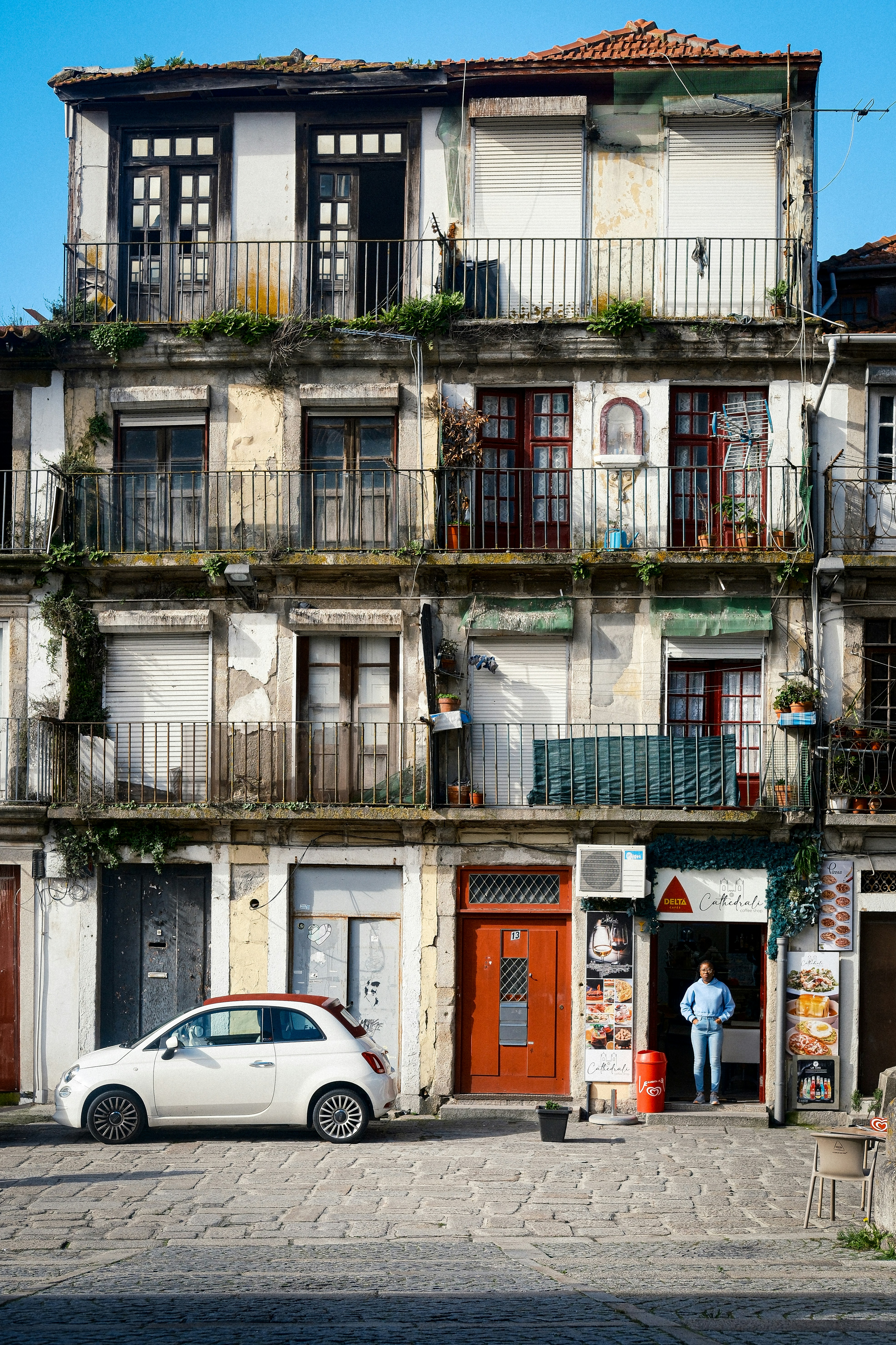A white car parked in front of a tall building