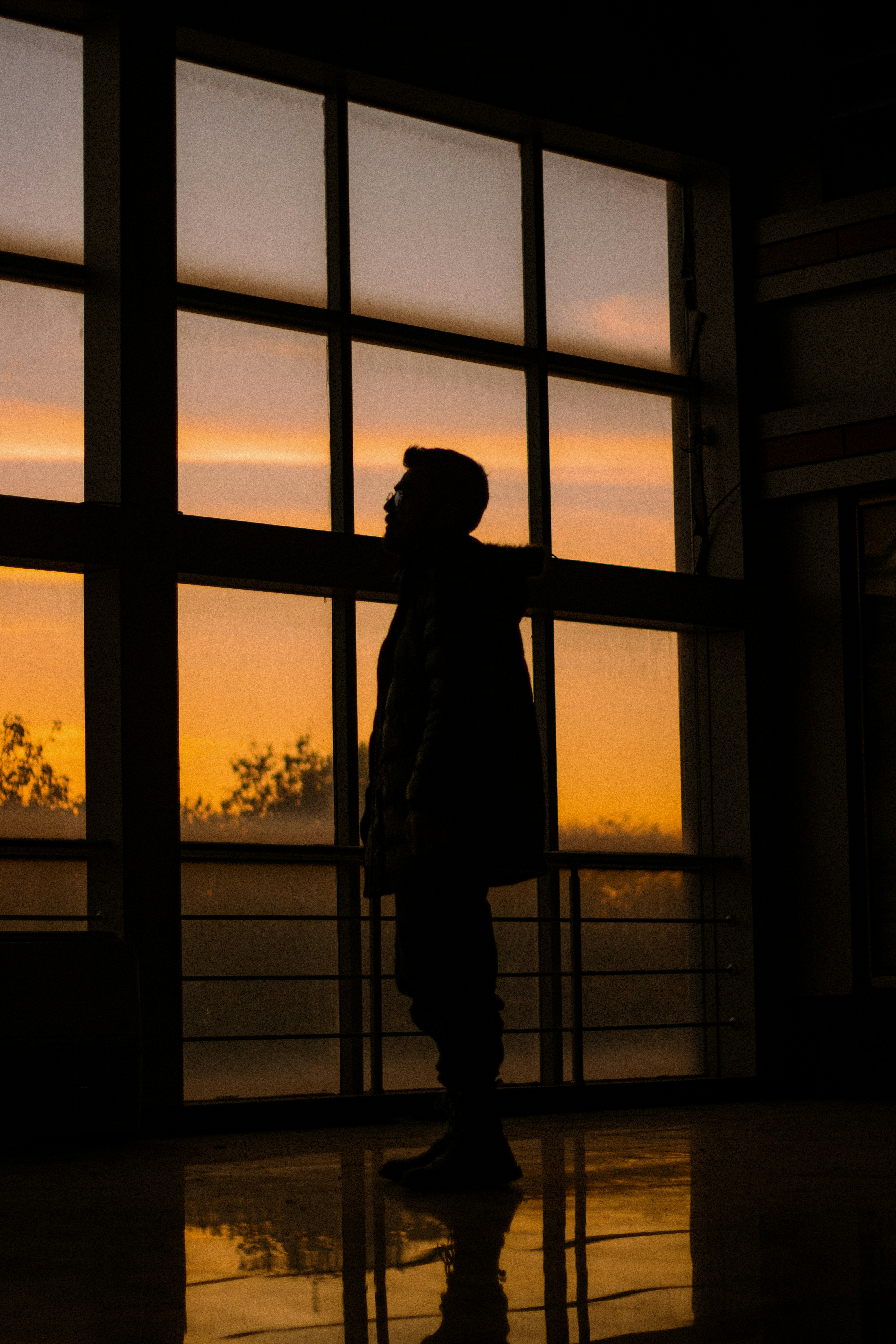 A silhouette of a person standing in front of a window