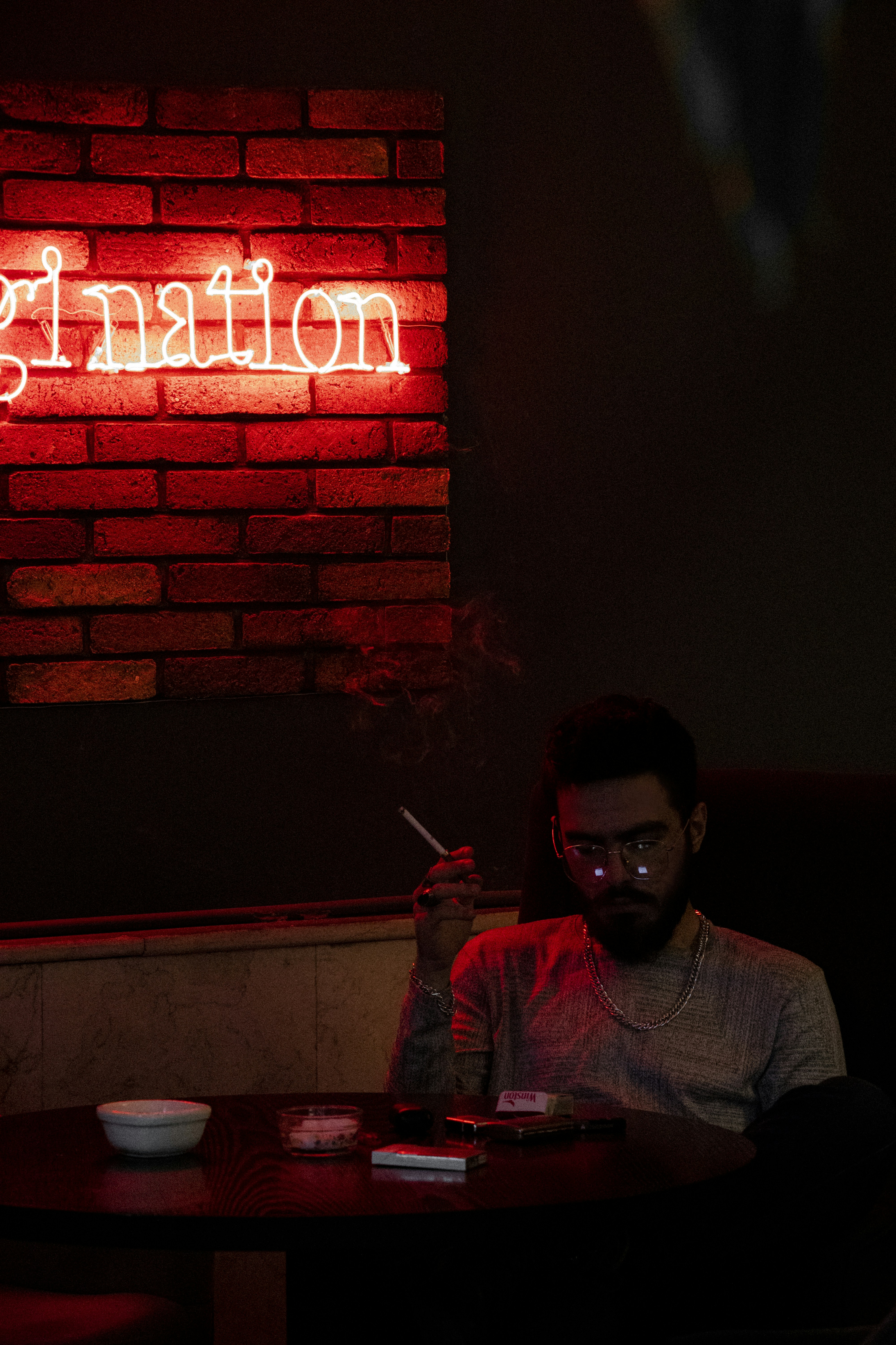 A man sitting at a table in front of a neon sign